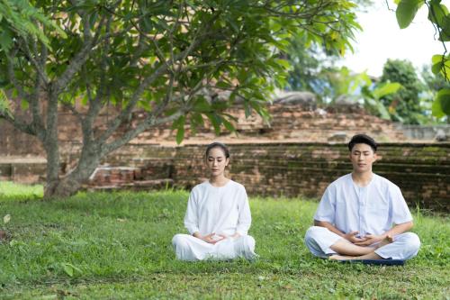 two men sitting in the grass in meditation at Athita The Hidden Court Chiang Saen Boutique Hotel in Chiang Rai