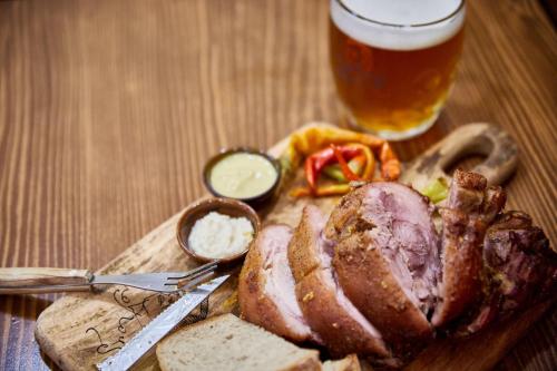 a plate of meat and bread with a glass of beer at Hotel Slunce in Rýmařov