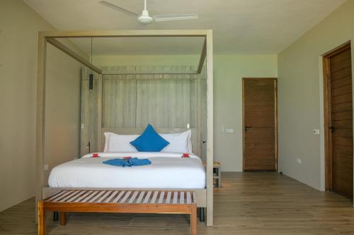a bedroom with a large white bed with blue pillows at Villa Bluu Zanzibar in Jambiani