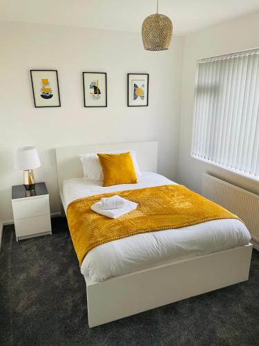 a bedroom with a large bed with a yellow blanket at Wolverhampton Walsall Large 3 Bedrooms 5 bed House Perfect for Contractors Short & Long Stays Business NHS Families Sleeps up to 5 people Private Garden Driveway for 2 large Vehicles Close to City Centre M6 M54 and Walsall Willenhall Cannock in Wolverhampton