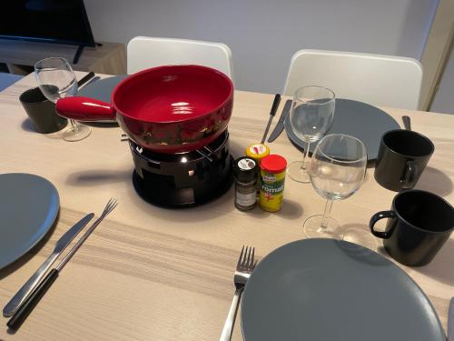 a table with a red pot and glasses on it at Super central - appartement 2,5pcs à Leukerbad in Leukerbad