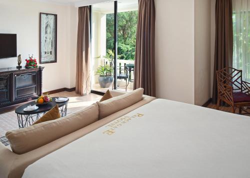 a bedroom with a large bed and a living room at Palace Gate Hotel & Resort By EHM in Phnom Penh
