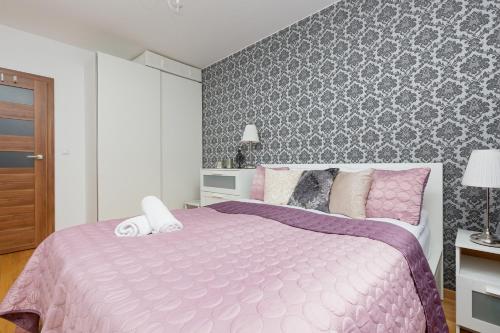 sypialnia z różowym łóżkiem i ścianą w obiekcie Atrium Ursus Warsaw Apartments by Renters w Warszawie