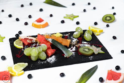 a black plate of fruit on a white table at Logis hôtel et restaurant La Bastide Cabezac in Bize-Minervois