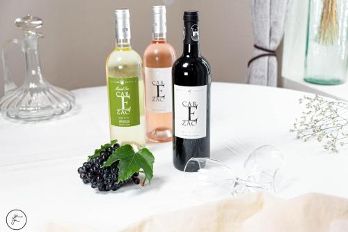 two bottles of wine and a bunch of grapes on a table at Logis hôtel et restaurant La Bastide Cabezac in Bize-Minervois