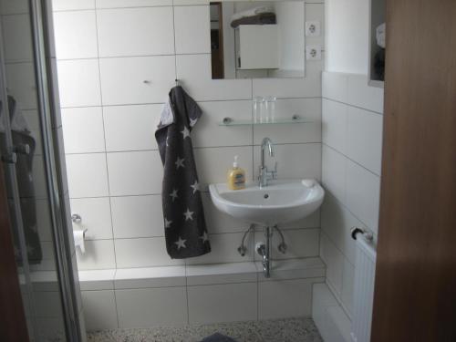 a white bathroom with a sink and a mirror at Pumuckl in Husum