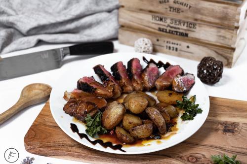 a plate of meat and potatoes on a table with a knife at Logis hôtel et restaurant La Bastide Cabezac in Bize-Minervois