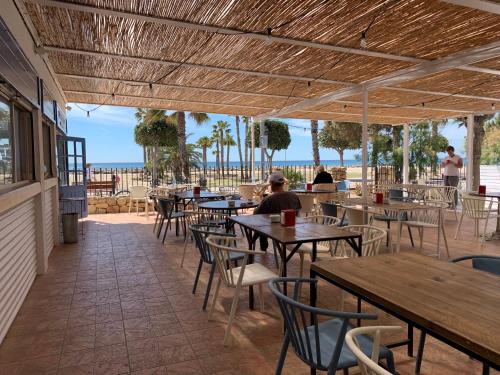 a restaurant with tables and chairs and the beach at Camping Joan Bungalow Park in Cambrils