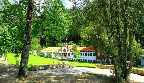 a large white house with trees in front of it at Pensão Continental Machado in Caldelas