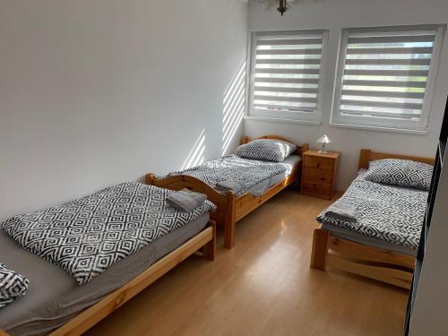 two twin beds in a room with two windows at W apartmán in Teplice nad Metují