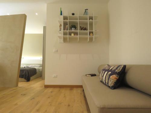 uma sala de estar com um sofá e um quarto em Ariosti Apartment em Bolonha