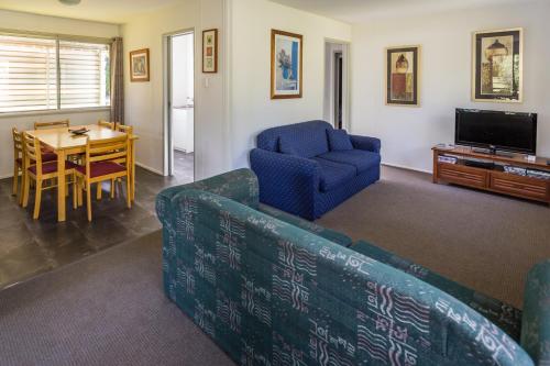 sala de estar con sofá, mesa y TV en Scenic Rim Motel, en Aratula