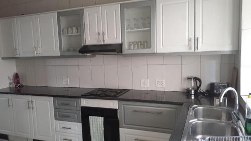 Una cocina con gabinetes blancos y un horno de estufa. en ocean palace self catering lodge, en Durban