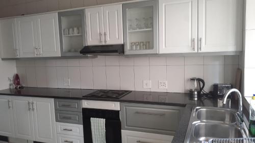 a kitchen with white cabinets and a stove top oven at ocean palace self catering lodge in Durban