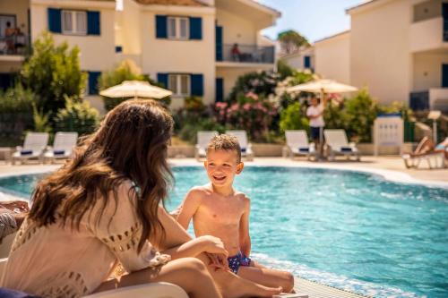 a young boy sitting in a swimming pool next to a woman at Aminess Vival Port9 Residence in Korčula