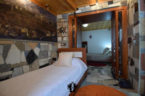 1 dormitorio con 1 cama en una habitación con una pared de piedra en Guest House Bake, en Gjirokastra