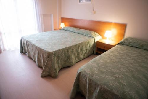 a hotel room with two beds and two lamps at Hotel Umberto in Rosolina Mare