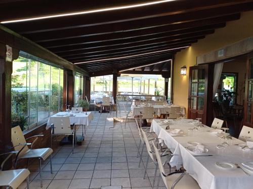 a restaurant with white tables and chairs and windows at El Tejo de Comillas in Comillas