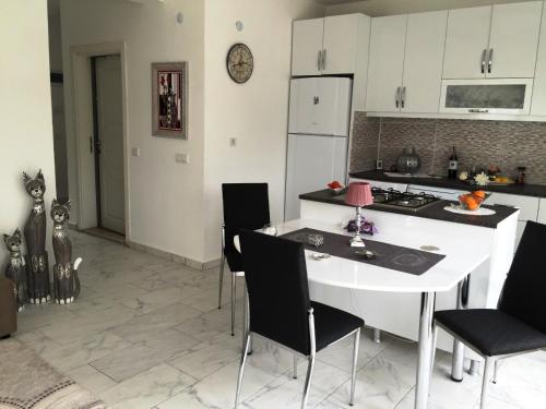 a kitchen with a white table and black chairs at BELKA GOLF RESİDENCE Deluxe apt Poolside BELEK in Belek