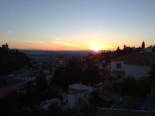 una puesta de sol sobre una ciudad con casas y edificios en Apartamentos miradores de granada, en Granada