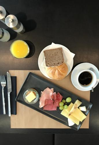 a table with a plate of food with a sandwich and cheese at Blackhome Graz I contactless check-in in Graz