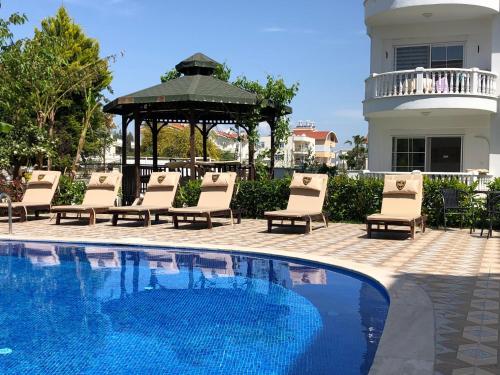 a group of chairs and a gazebo next to a pool at BELKA GOLF RESİDENCE Poolside apt1 Belek in Belek