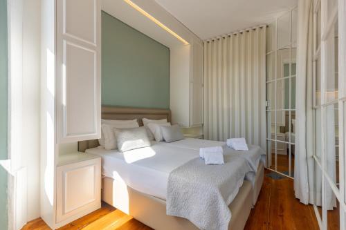 1 dormitorio con 1 cama blanca grande con almohadas blancas en CLUBE Charming Apartments - Ribeira, en Oporto