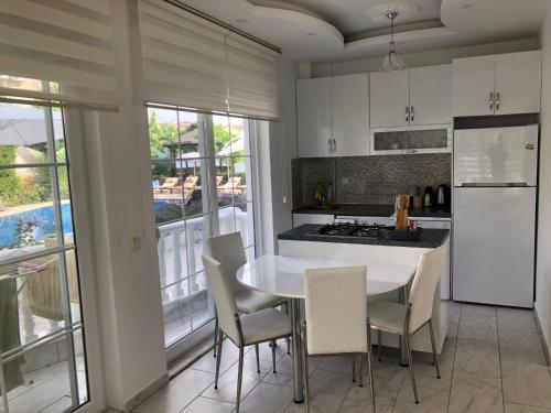 a kitchen with a table and chairs and a refrigerator at BELKA GOLF RESİDENCE Poolside apt1 Belek in Belek