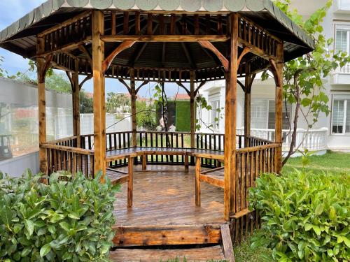a wooden gazebo in the middle of a yard at BELKA GOLF RESİDENCE Poolside apt1 Belek in Belek