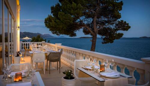 een restaurant met tafels en stoelen op een balkon met uitzicht op het water bij Aminess Bellevue Village in Orebić