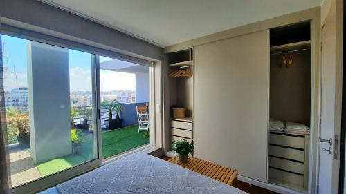 Un dormitorio con una gran ventana con vistas. en Jardim na Praia, en Matosinhos