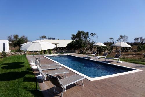 a swimming pool with lounge chairs and umbrellas at giardino del tempo in Merine