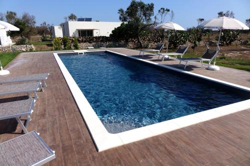 a swimming pool with chairs and a deck at giardino del tempo in Merine