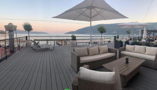 a deck with couches and a table and an umbrella at Tamaris Apartmani in Herceg-Novi