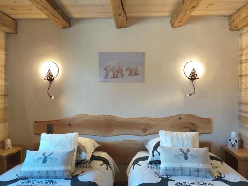 a bedroom with two beds and two lights on the wall at Le Granit in Combloux