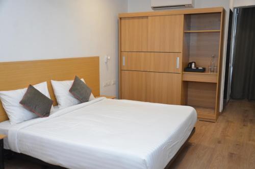 a bedroom with a large white bed and a cabinet at Lords Eco Inn Belagavi in Belgaum