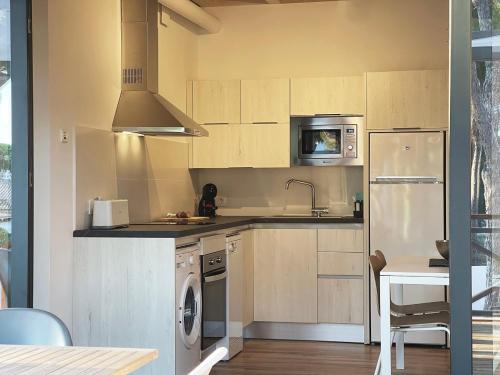 a kitchen with a washer and a sink and a microwave at Apartamentos Biopasivos Living Pura Madera in Chiclana de la Frontera