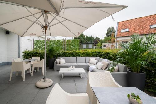 a patio with a couch and an umbrella at ibis Styles Nieuwpoort in Nieuwpoort