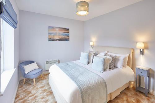 een witte slaapkamer met een bed en een blauwe stoel bij Host & Stay - Starboard Bow in Whitby