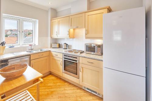 een keuken met houten kasten en een witte koelkast bij Host & Stay - Starboard Bow in Whitby