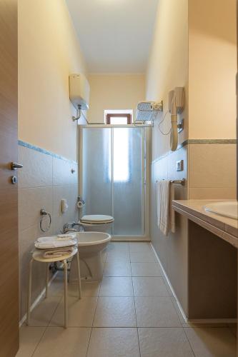 a bathroom with a shower and a toilet and a sink at Club Azzurro Hotel & Resort in Porto Cesareo