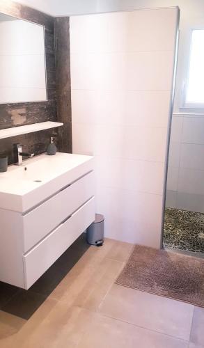 une salle de bain avec un lavabo blanc et un miroir dans l'établissement Charmante villa dans un village paisible aux portes d'Uzès et des Cévennes, à Saint-Hippolyte-de-Caton