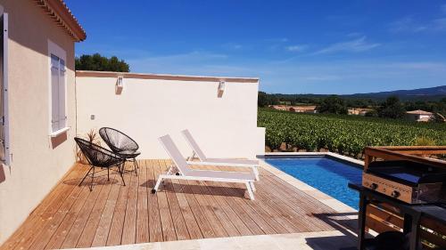 une terrasse en bois avec une chaise et une piscine dans l'établissement Charmante villa dans un village paisible aux portes d'Uzès et des Cévennes, à Saint-Hippolyte-de-Caton