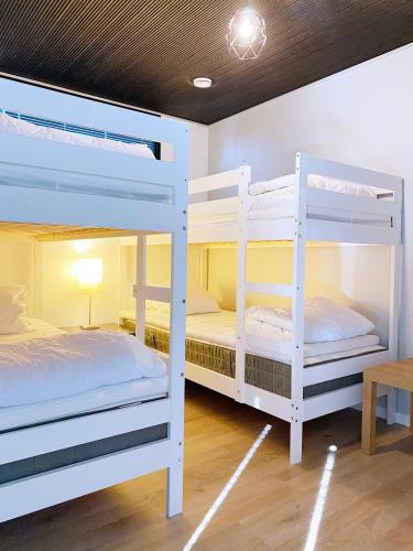 two white bunk beds in a room with a table at Reelinki Seafront Villa Aava in Pori