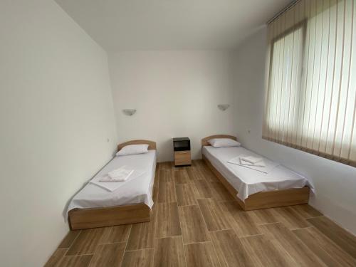 two beds in a room with a window and wooden floors at Къща за гости Краси in Krapets