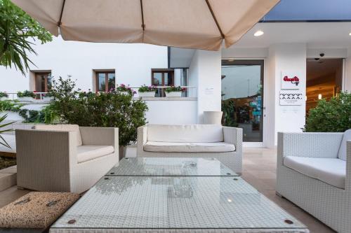 a patio with a table and chairs and an umbrella at Club Azzurro Hotel & Resort in Porto Cesareo