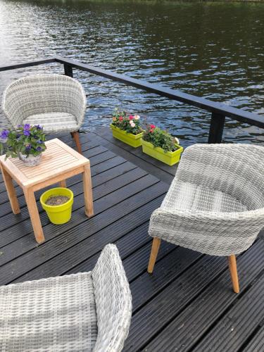 two chairs and a table on a dock next to the water at gardenhouse mariposa in Badhoevedorp