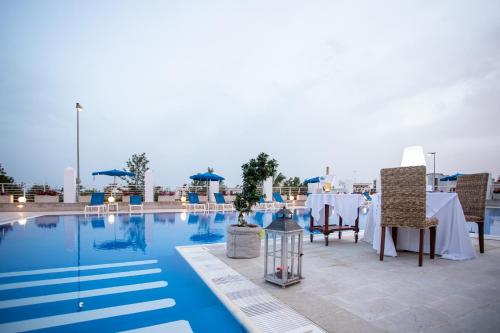 a table and chairs sitting next to a pool at Club Azzurro Hotel & Resort in Porto Cesareo
