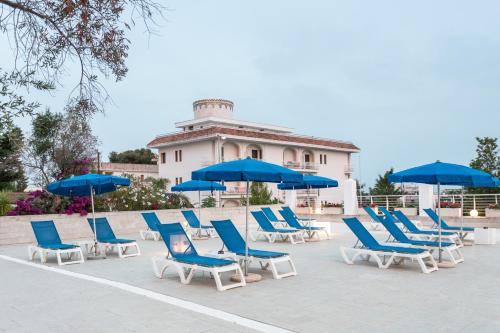 a group of blue chairs and umbrellas in front of a building at Club Azzurro Hotel & Resort in Porto Cesareo