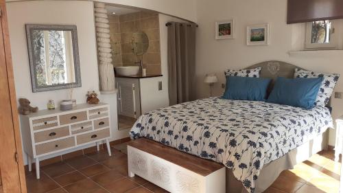 een slaapkamer met een bed met blauwe kussens en een dressoir bij Le Jardin du Cannet in Bagnols-en-Forêt